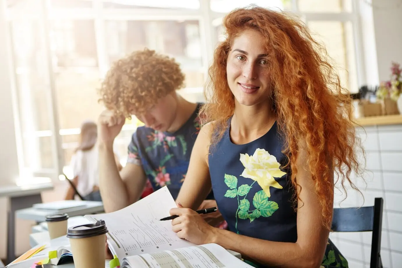 Hermosa mujer sentada en una cafetería haciendo ejercicios en su cuaderno.