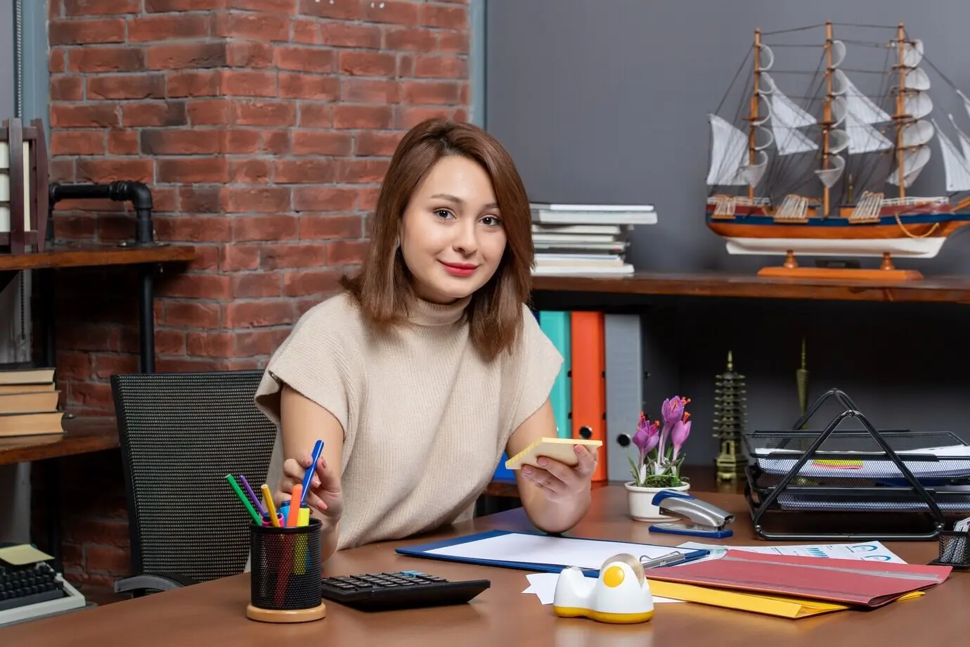 Vista frontal de una mujer de negocios que toma un bolígrafo mientras está sentada frente a un escritorio en una oficina.